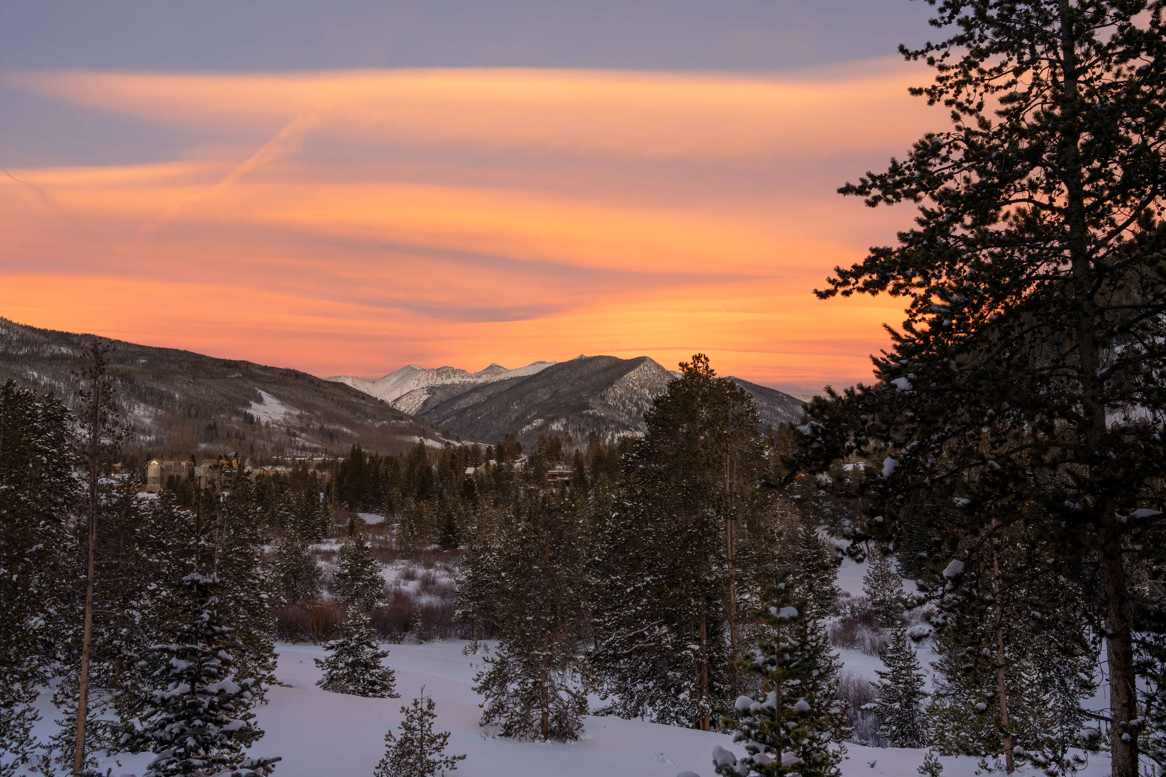 Orange hazy sky over looking a snowy mountain. 