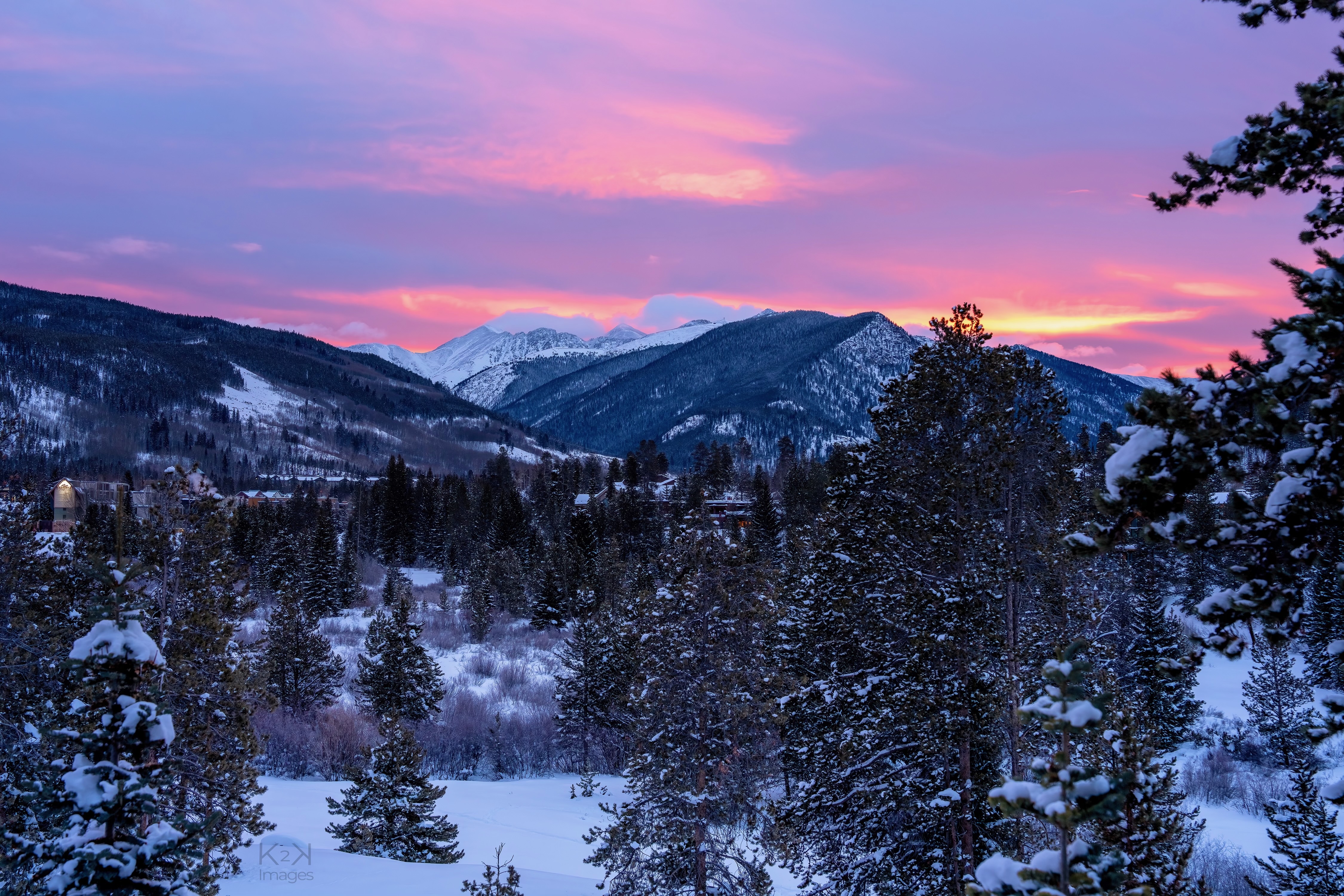 Pink hued sun rising over snow covered Dercum Mountain in Keystone.
